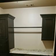 Empty closet nook with dark cabinets, a shelf, and a granite countertop below.