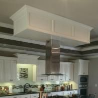 Modern kitchen with white cabinets, stainless steel range hood, and gray walls