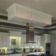 Modern kitchen with white cabinets, stainless steel range hood, and a large ceiling-mounted hood box