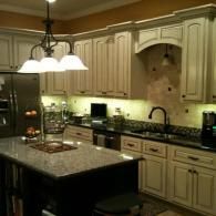 Elegant cream kitchen with granite island, pendant lights, and stainless steel appliances