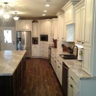 Bright white kitchen with granite counters, dark wood floors, and stainless appliances