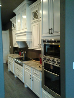 White kitchen with built-in oven, stovetop, sink, and cabinets along a narrow wall.