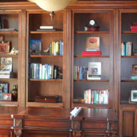 Wooden bookcase with books and framed photos in a warmly lit room