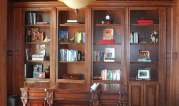 Wooden built-in bookcase with books and framed photos in a warmly lit room