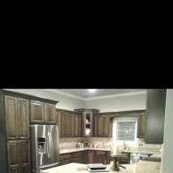 Modern kitchen with dark wood cabinets, stainless steel fridge, and a window over the sink