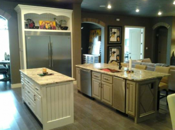 Spacious kitchen with stainless steel fridge, island, and beige cabinets under recessed lighting