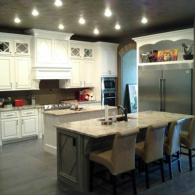 Modern kitchen with white cabinets, stainless steel fridge, and a large island with stools