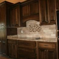 Wooden kitchen cabinets with beige tile backsplash and granite countertop
