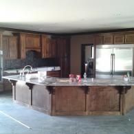 Spacious kitchen with dark wood cabinets, large island, and stainless steel refrigerator