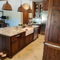 Modern kitchen with island, marble countertop, wood cabinets, and pendant lights