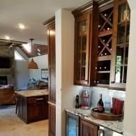 Modern kitchen and bar area with wood cabinets, granite counter, and wine display shelves