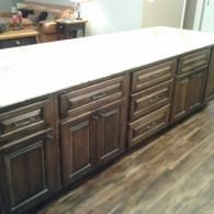 Kitchen island with dark wood cabinets and a white countertop on a wood floor