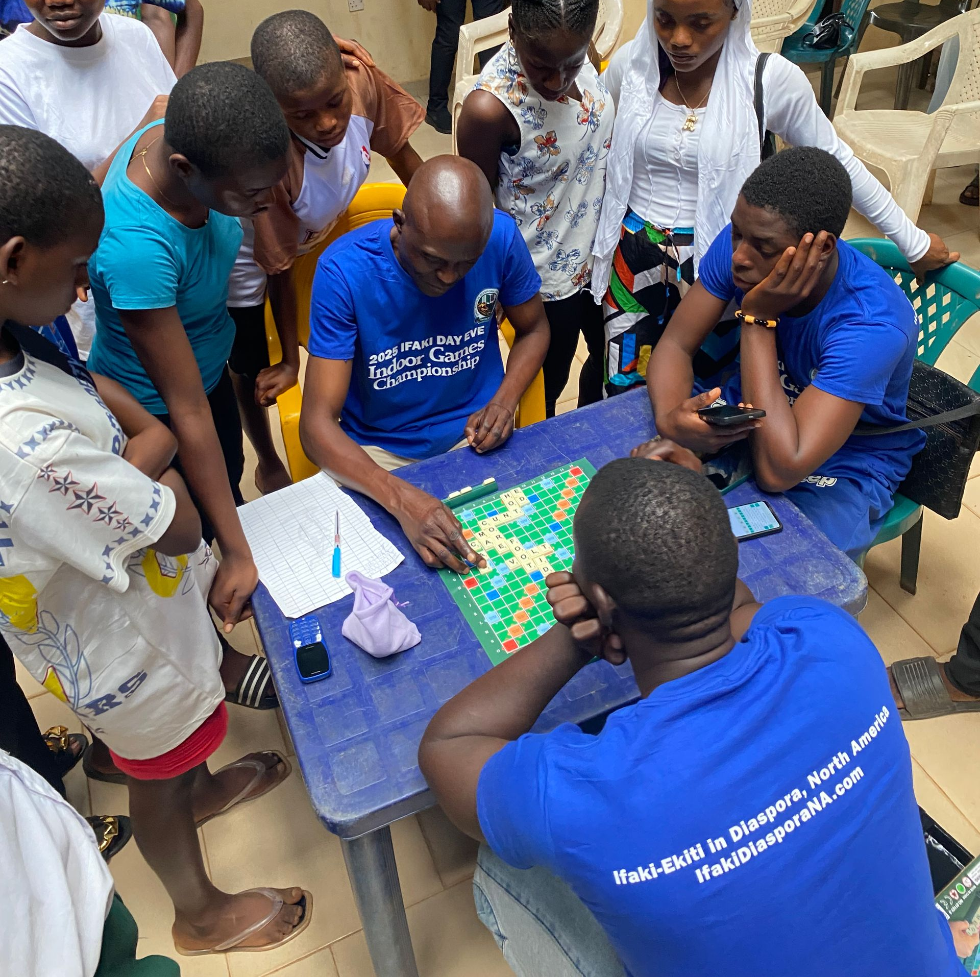 People playing a word game, gathered around a table outdoors.