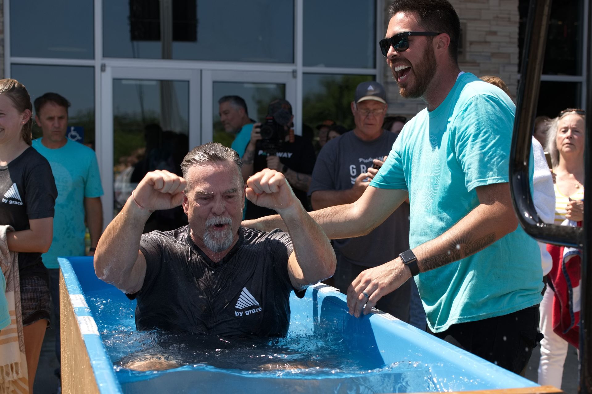 image of a middle-aged man in a baptism tank, another man standing nearby smiling