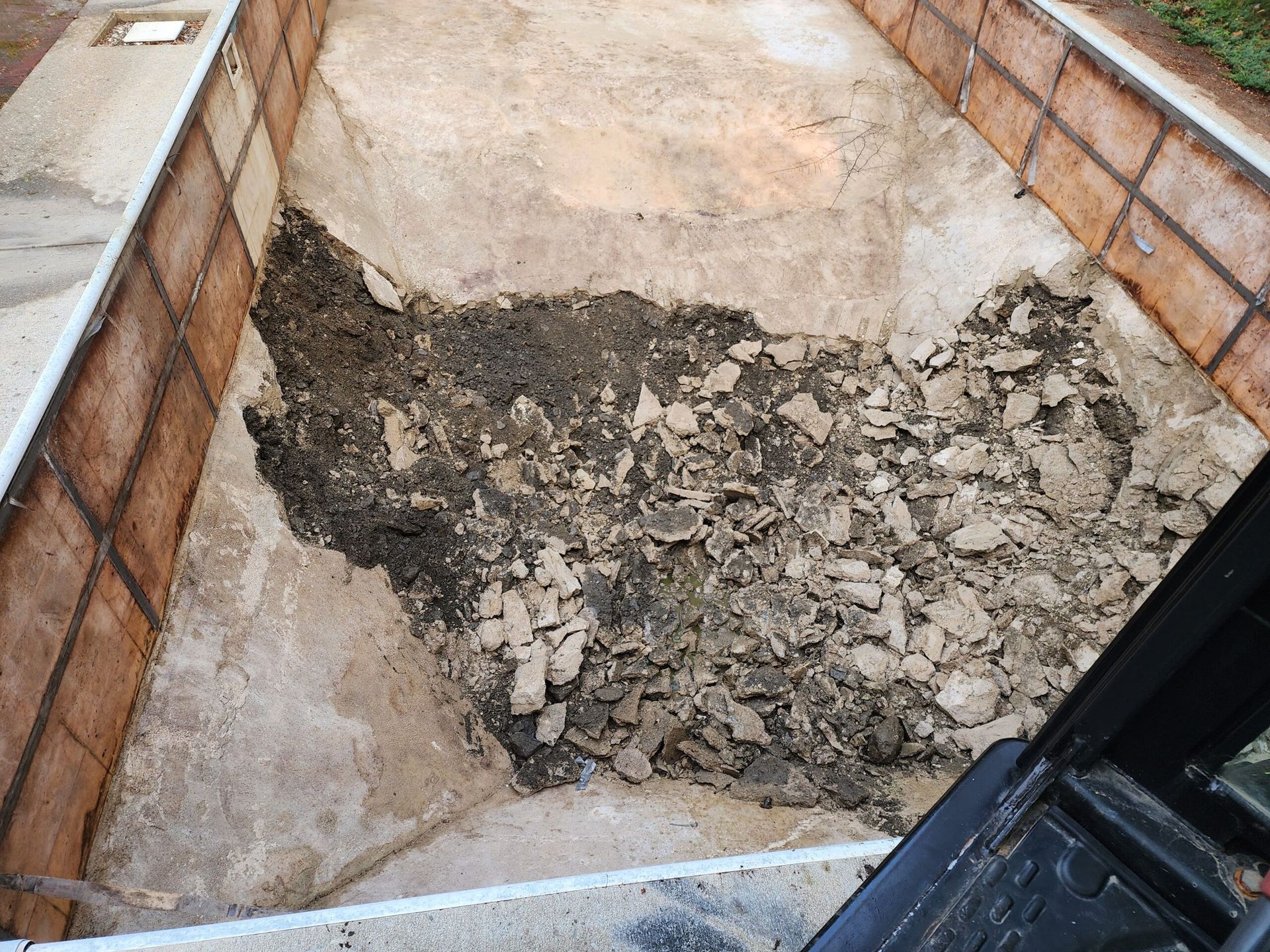 A pile of dirt is sitting on the ground next to a brick wall.