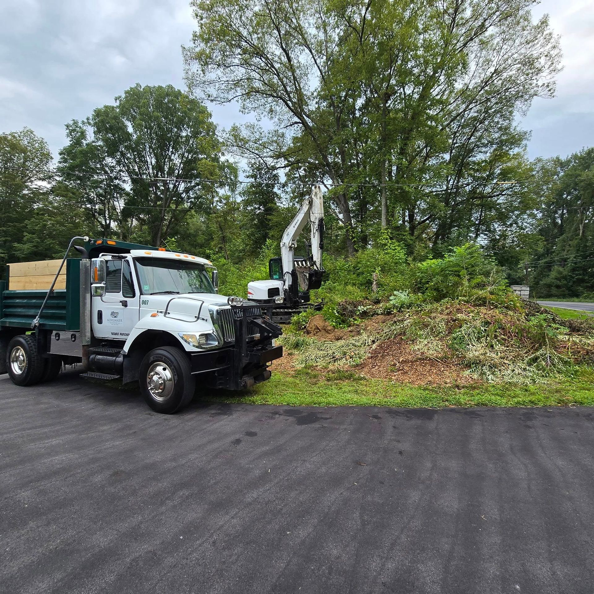 A dump truck is parked on the side of the road next to a pile of brush.