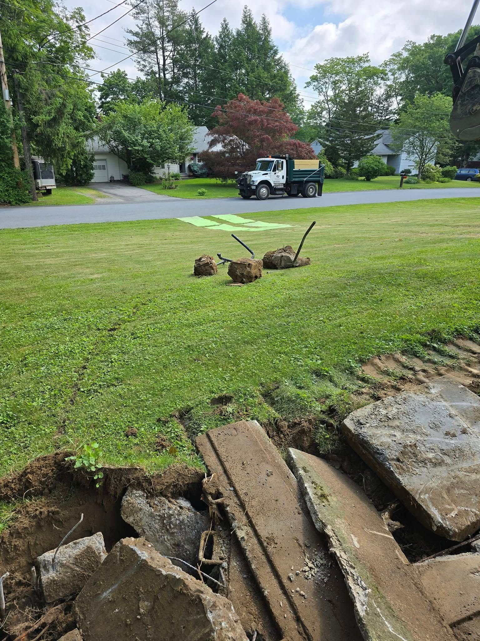 A truck is parked in the grass next to a hole in the ground.