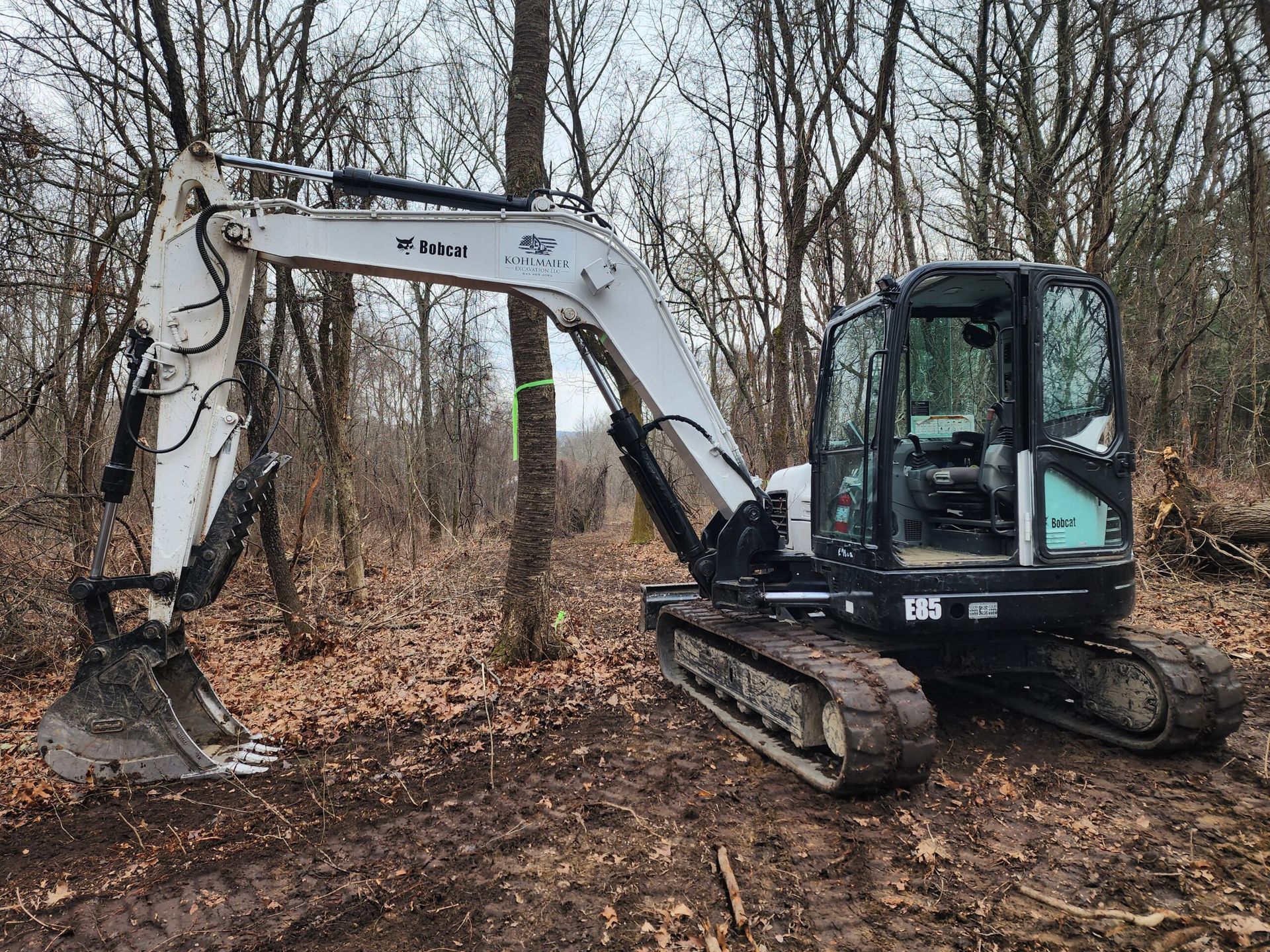 A bobcat excavator is sitting in the middle of a forest.