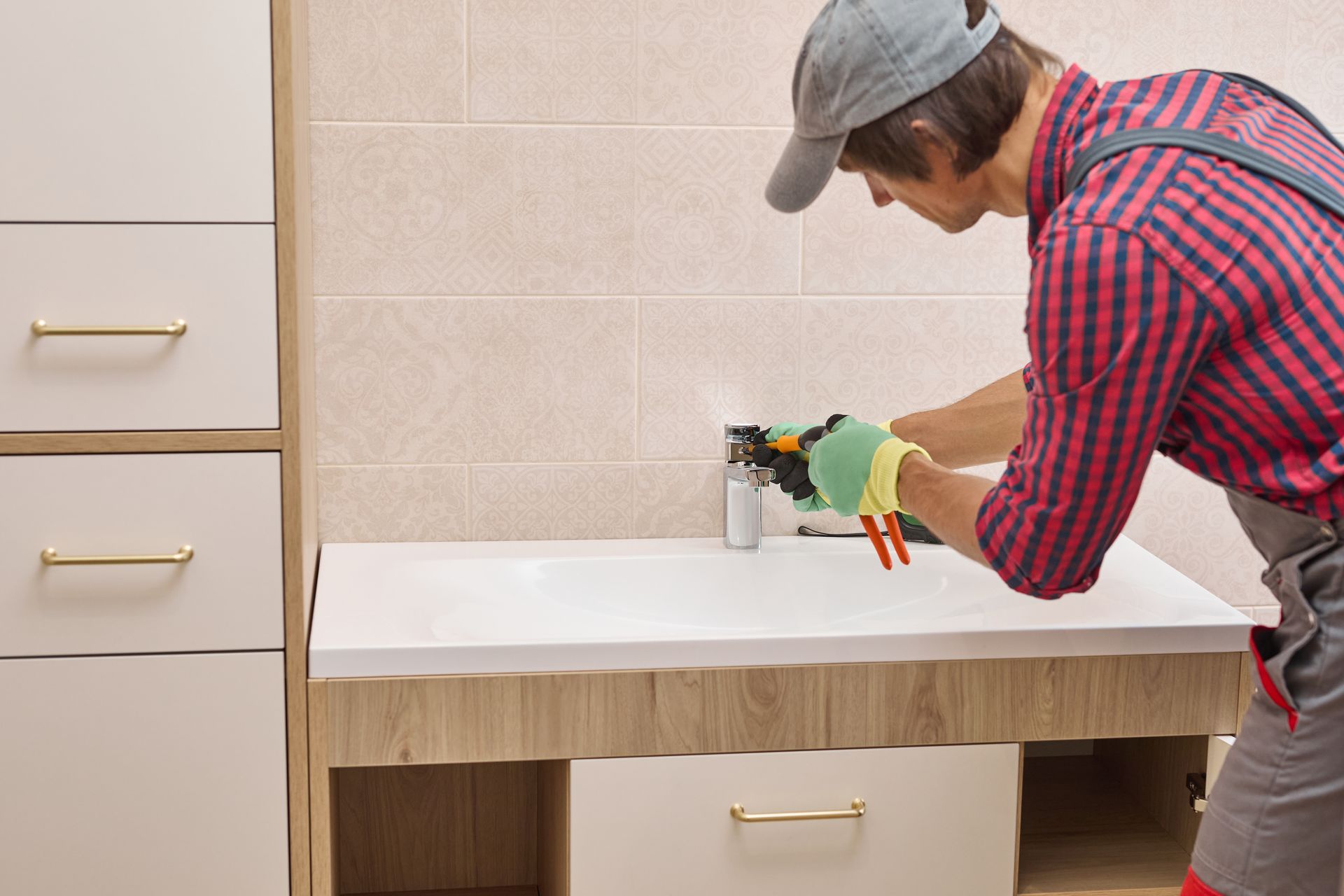 Person installing or repairing a bathroom sink faucet with hand tools during a renovation.