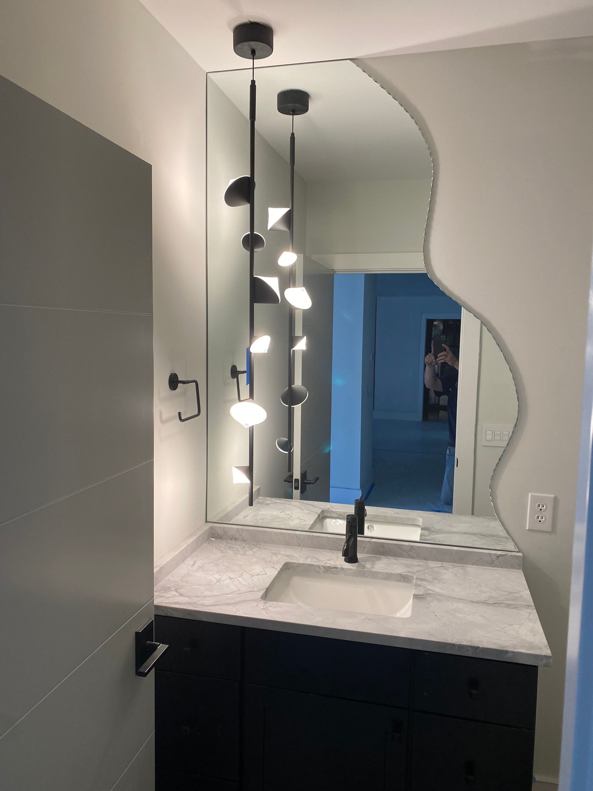 Vanity with unique mirror and modern light fixture.