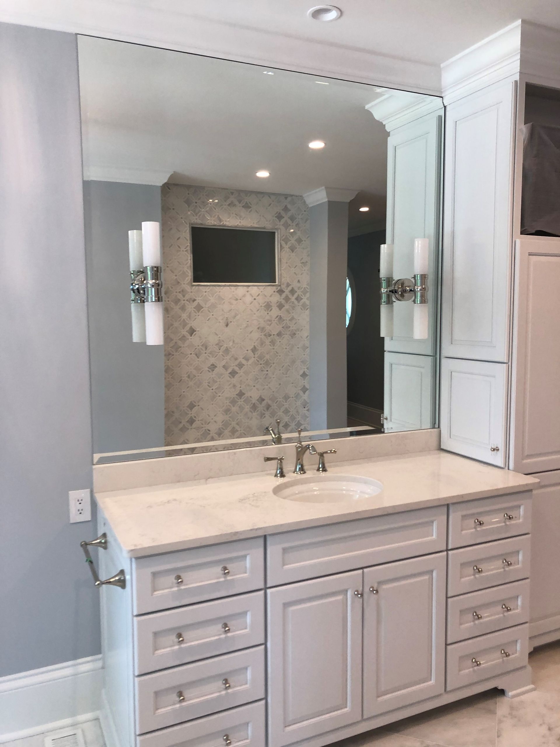 Bathroom with white vanity, large mirror, and decorative wall tiles.
