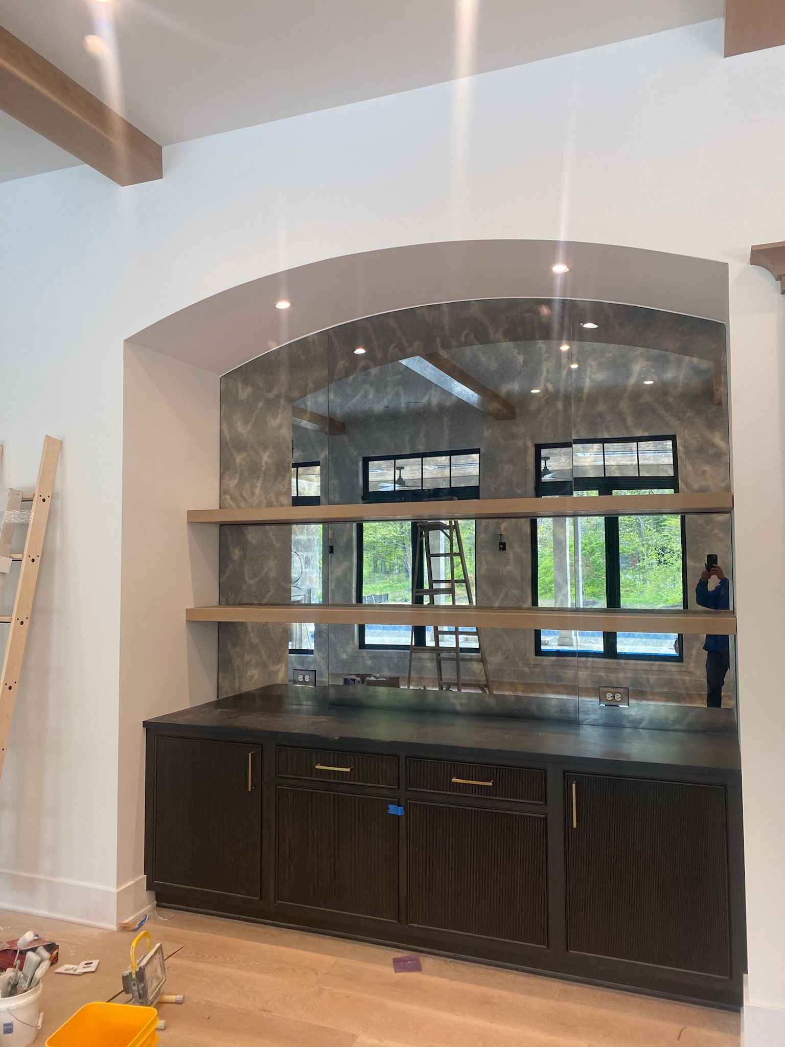 Built-in dark brown cabinets and floating shelves inside an arched alcove with a light-colored wall.