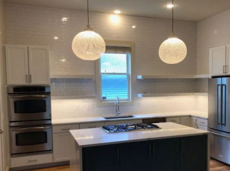 Modern kitchen with white cabinets, stainless steel appliances, and a dark blue island.