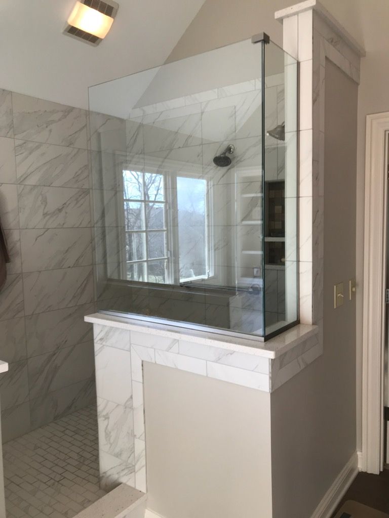 Glass shower enclosure with marble tile in a bathroom.