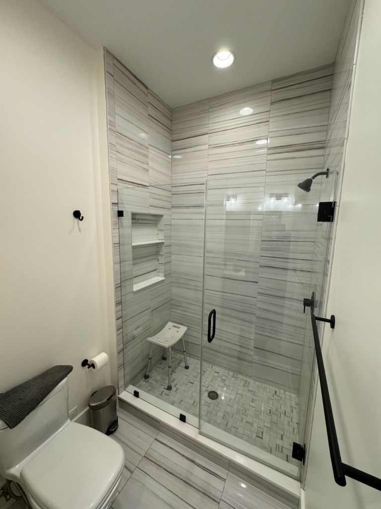 Modern bathroom with glass shower, tiled walls, and toilet.