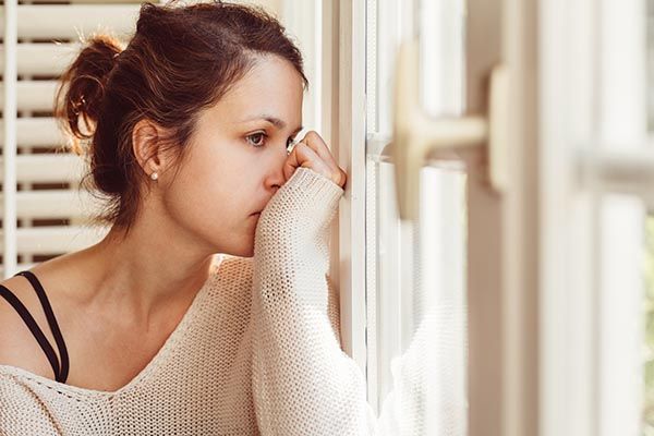a woman is looking out of a window with her hand on her face .