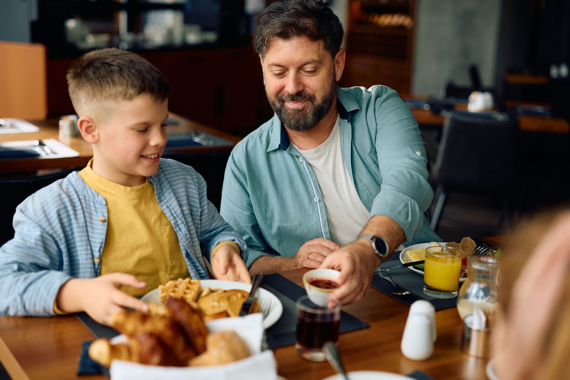 Happy father and son eating during family breakfast. Happy father and son eating during family breakfast.