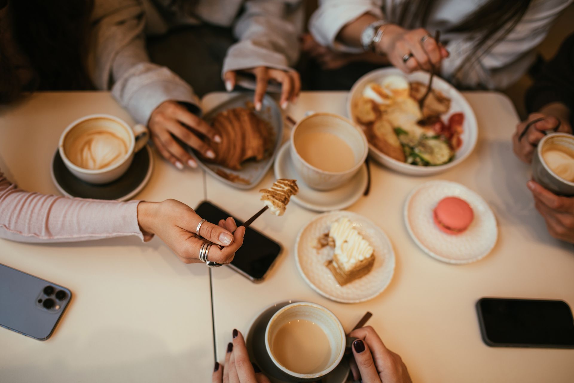 A diverse group of friends savoring coffee and pastries at a cozy, local breakfast restaurant.