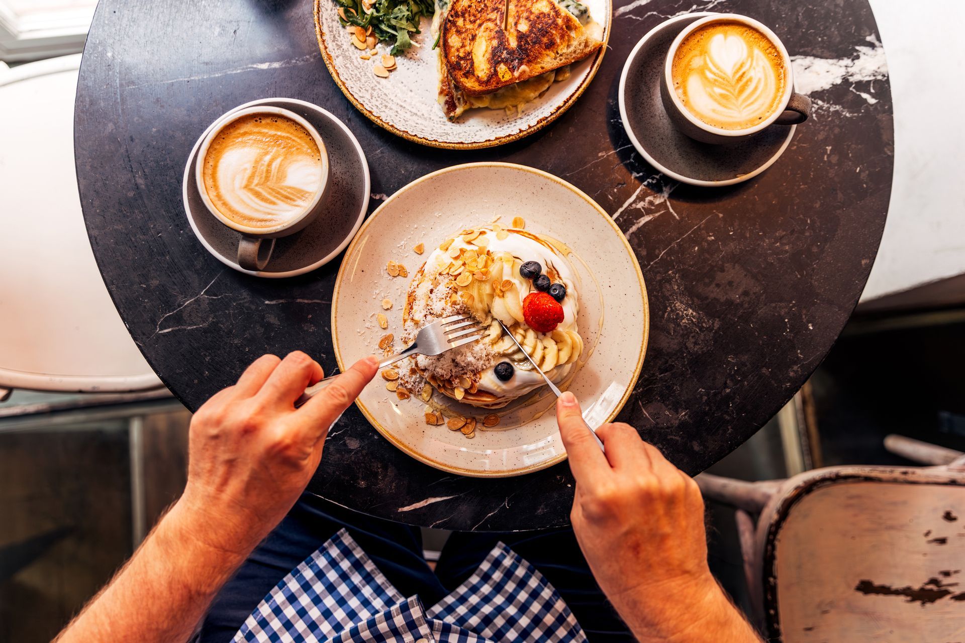 Table with pancakes, coffee, and omelet at a cozy family breakfast restaurant setting.