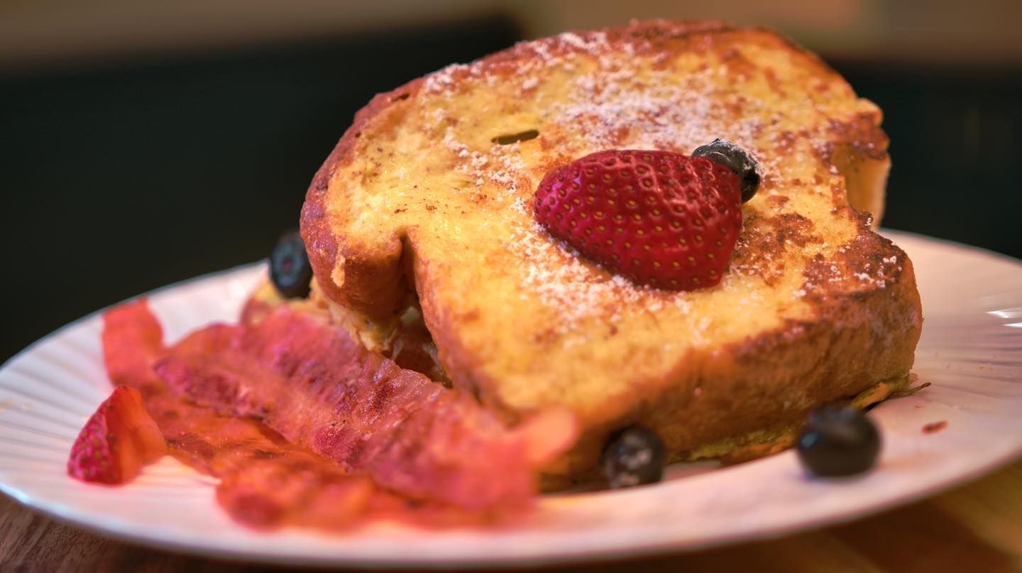 A piece of french toast with strawberries and blueberries on a plate.