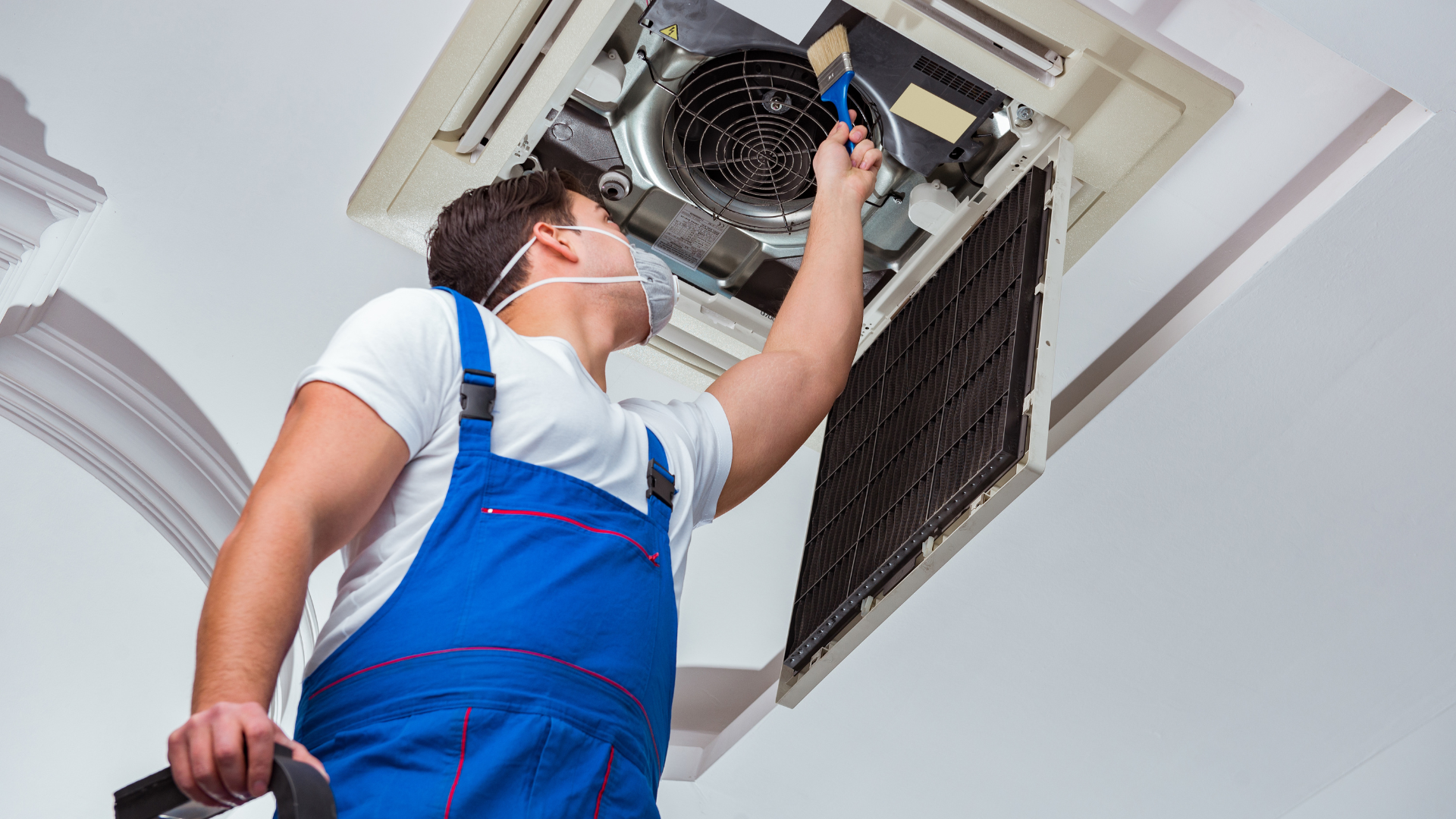 a man wearing a mask is working on an air conditioner .