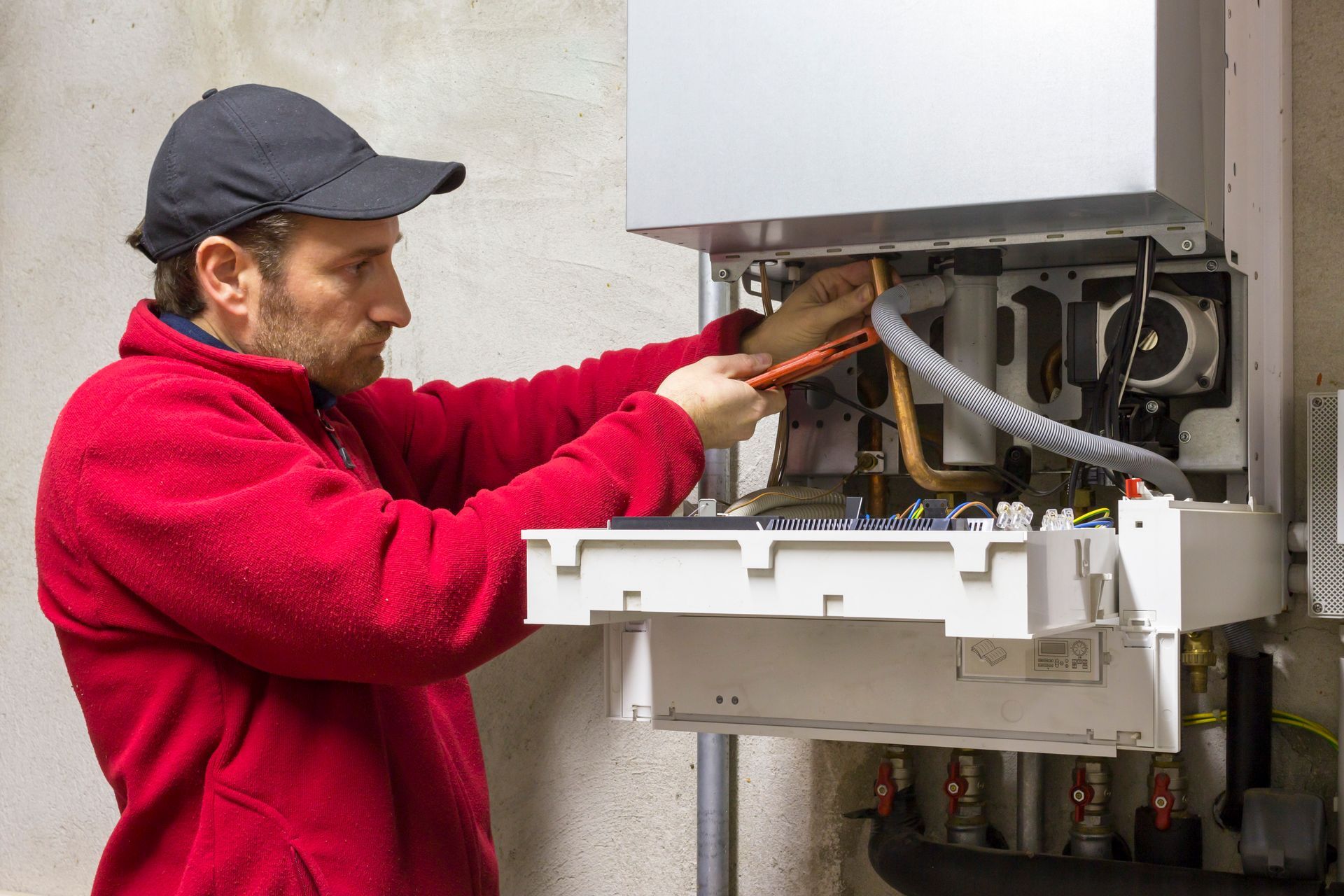 a man wearing a hard hat and gloves is installing an air conditioner .