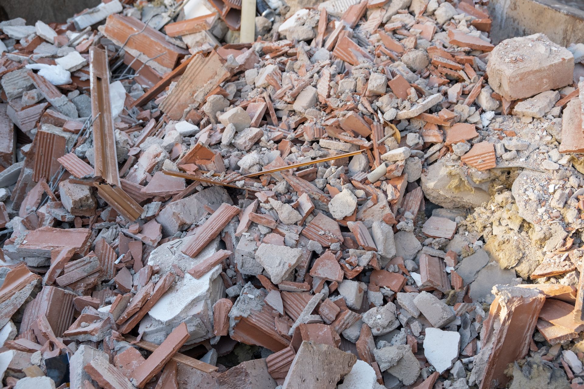Pile of broken bricks and rubble from construction debris, with dust and scattered fragments.