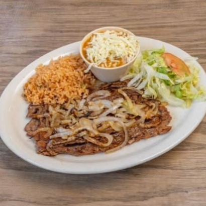Plate with sliced grilled meat, rice, coleslaw, and salad on a wooden table
