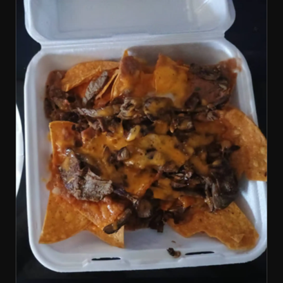 Open foam takeout box with nachos topped with melted cheese, meat, and sauce
