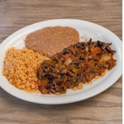 Plate with rice, refried beans, and a serving of sautéed vegetables on a wooden table