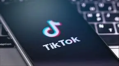 TikTok logo on a smartphone screen beside a laptop keyboard