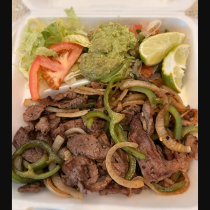 Takeout box with steak fajitas, sautéed peppers and onions, guacamole, lettuce, tomato, and lime wedges