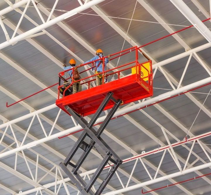 Two Men Are Working On A Scissor Lift In A Building — B2B Hire In Garbutt, QLD