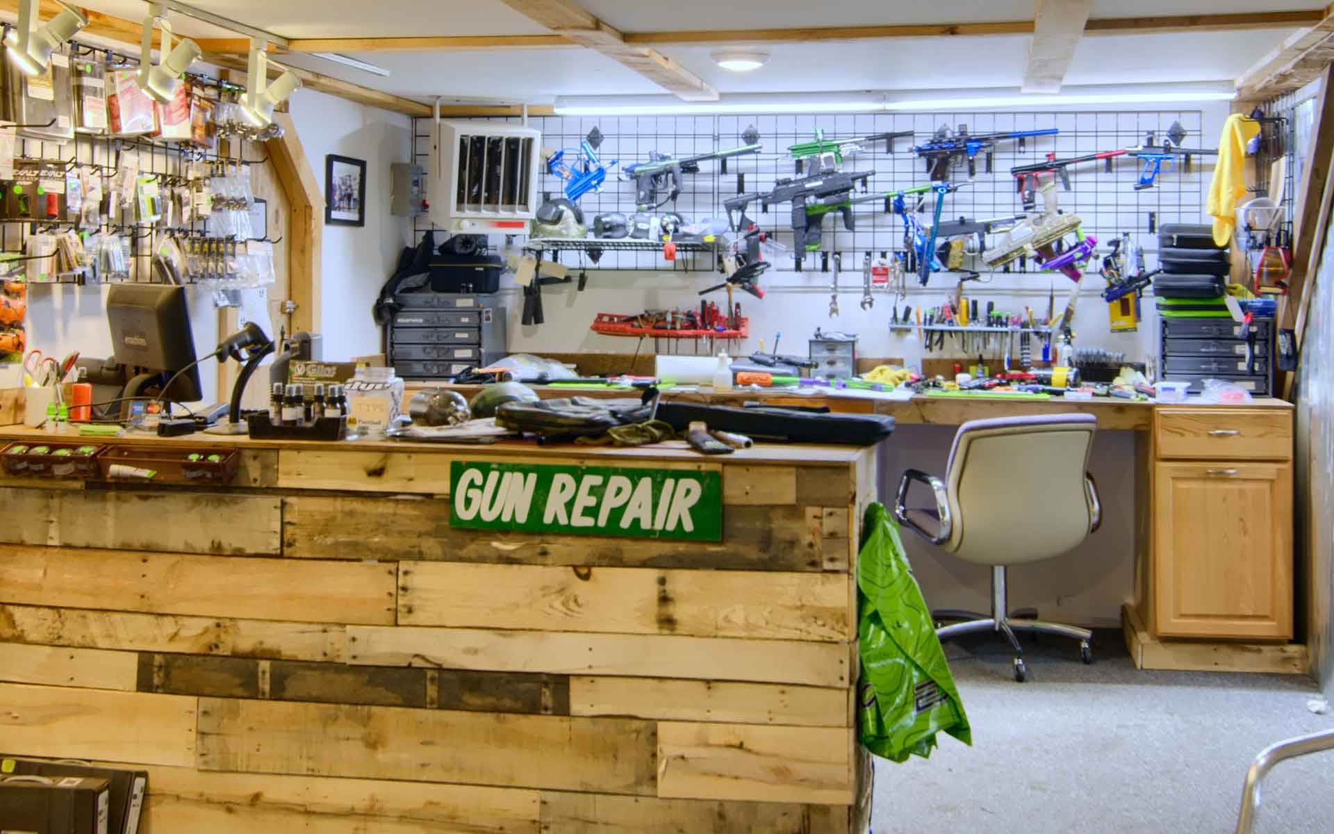 Gun repair shop. Wooden counter, tools, and guns on walls. Green sign 