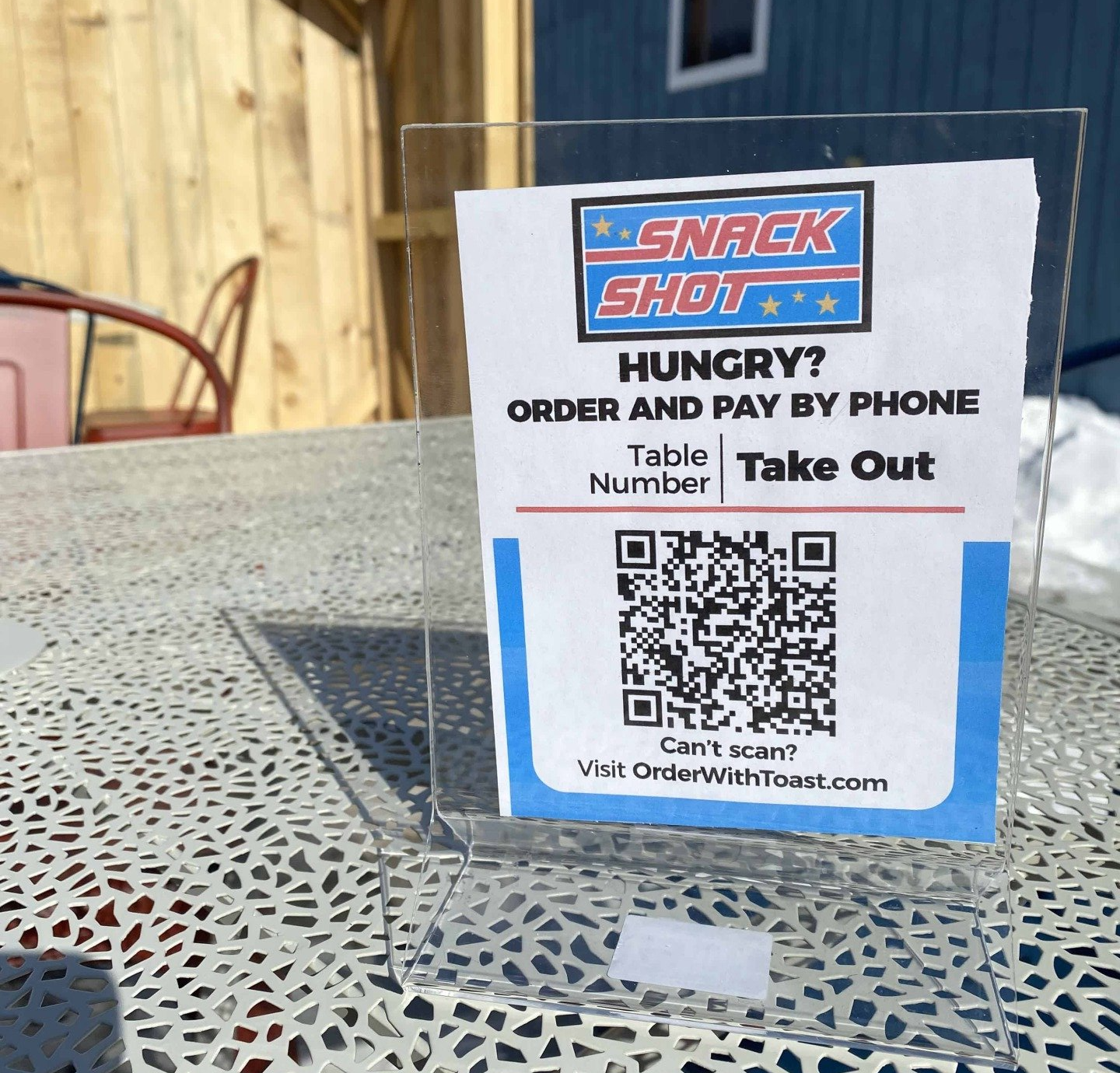 Sign at Snack Shot with QR code for phone ordering, placed on a table outdoors.