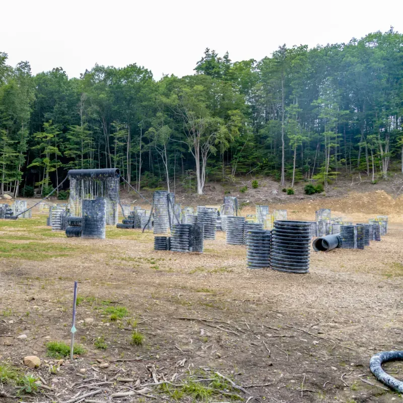 Paintball field with various bunkers and trees in the background.