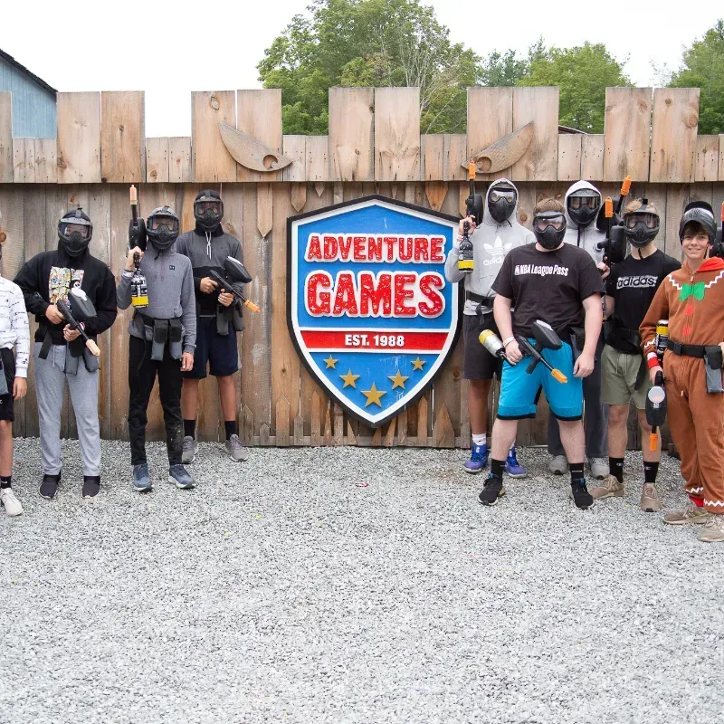 Group of people in paintball gear posing in front of an 