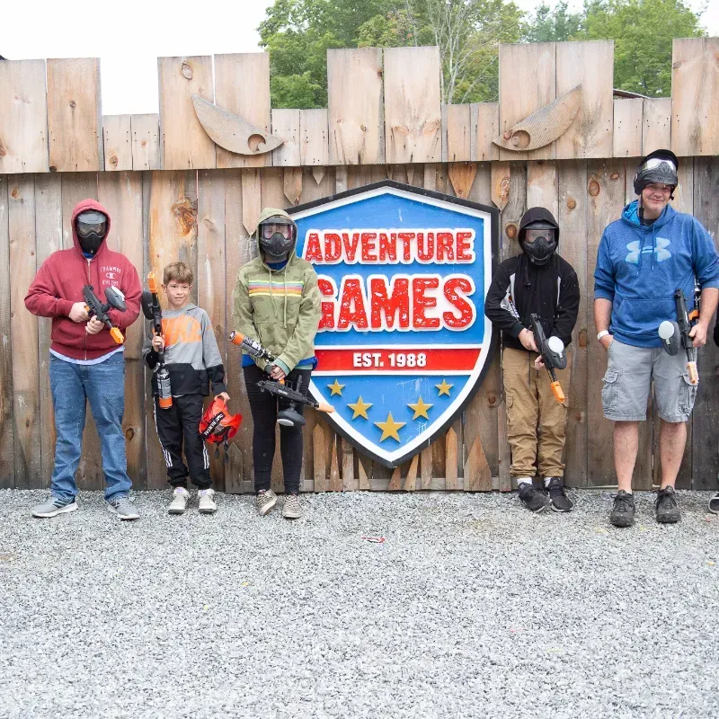 People in paintball gear standing by a sign for 