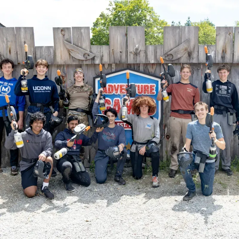 Group of teens posing with paintball guns at an Adventure Park, sunny day.