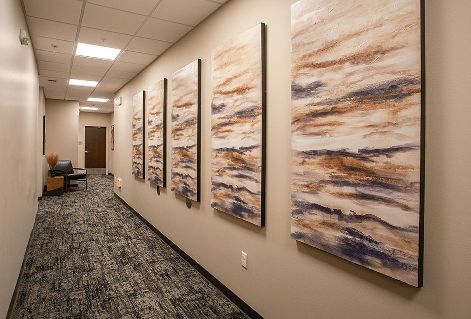 Office hallway with abstract wall art, beige walls, and patterned carpet